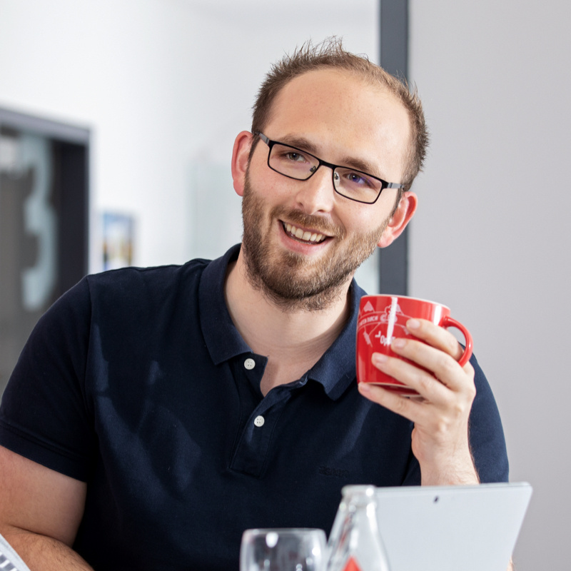 Optitime Mitarbeiter Carsten Wältermann im Gespräch und einem Kaffee in der Hand